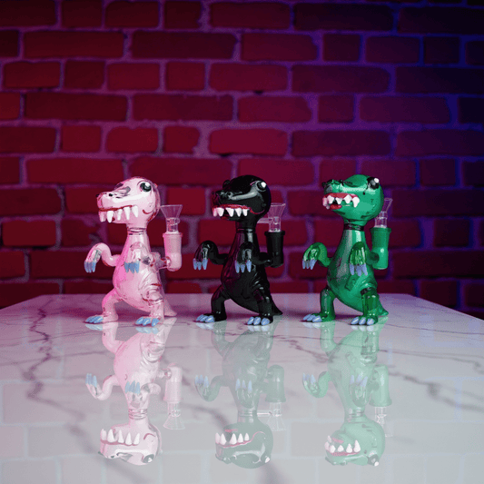 DinoRex Glass Bong - Borosilicate Glass DragonDinoRex Water Pipe - Three dinosaur - shaped glass bongs in pink, gray, and green lined up on smoky floor