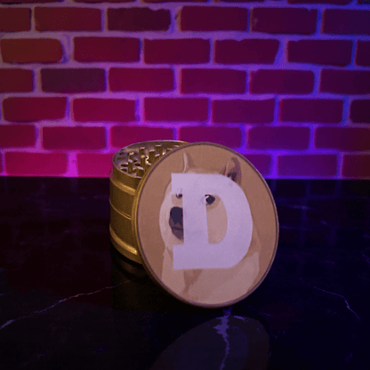 Doge Meme Herb Grinder - Gold - colored grinder with a dog design on a dark surface against a brick wall background