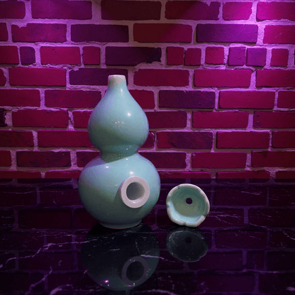 Glossy Blue Celadon Gourd Porcelain BongGlossy Blue Celadon Gourd Porcelain Bong and ceramic bowl are placed on a wooden surface.