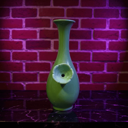 Glossy Green Celadon Bong with Flared TopGreen ceramic bong with a unique design ceramic bowl against a brick wall background