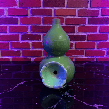 Glossy Green Celadon Gourd Porcelain BongGreen ceramic gourd - shaped bong on a dark surface with a brick wall background