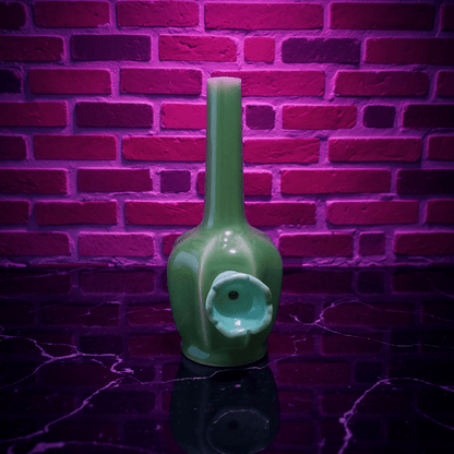 Glossy Green Flat - Sided Celadon Porcelain BongGreen ceramic bong with decorative elements against a brick wall.