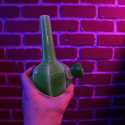 Glossy Green Flat - Sided Celadon Porcelain BongGreen ceramic pipe held against a brick wall with purple lighting