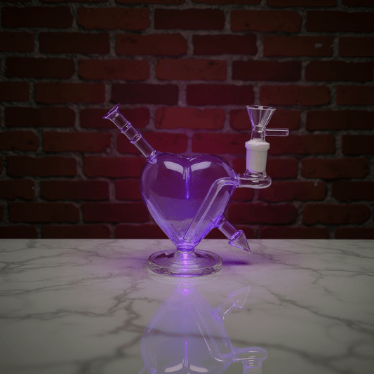 Heartpiercer glass bong - Purple VersionHeart - shaped glass bong with purple lighting on a reflective surface against a brick wall.