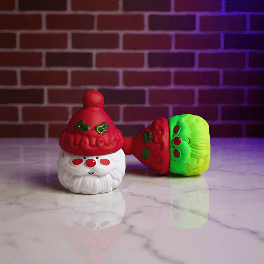 Herb Grinder – Holiday Edition grinders with a red hat and green and red body on a marble surface