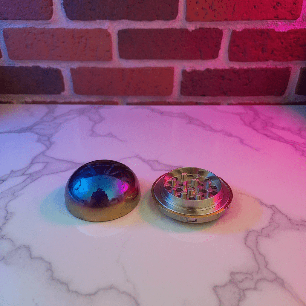 Holographic Ball Herb Grinder Metallic grinder on a marble surface with a brick wall background