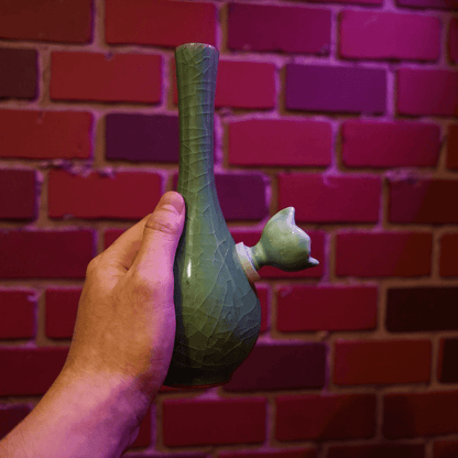 Ice - Crack Celadon Bong with Slim Neck DesignHand holding a green ceramic bong against a brick wall.