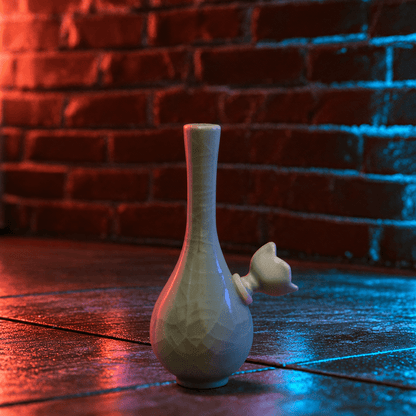 Ice-Crack Celadon Vase Bong with Slim Neck DesignA pale green ceramic bud vase with a textured glaze and a small bud-shaped neck, standing on a dark wooden surface against a red-lit brick wall.