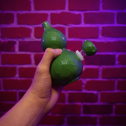 Ice - Crack Green Celadon Gourd Porcelain BongGreen ceramic bong held by a hand against a brick wall with purple lighting
