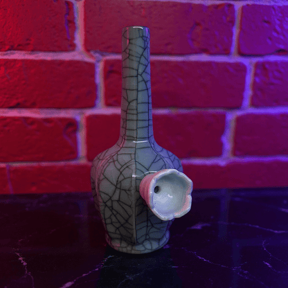 Ice - Crack Light Blue Celadon Flat - Sided Porcelain BongDecorative ceramic bong with unique design against a brick wall background