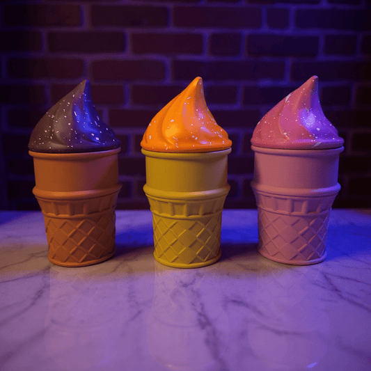 Ice Cream Herb Grinder – Cute 3 - Piece Swirl Cone SetThree ice cream cone - shaped herb grinder with colorful lids on a marble surface against a brick wall.