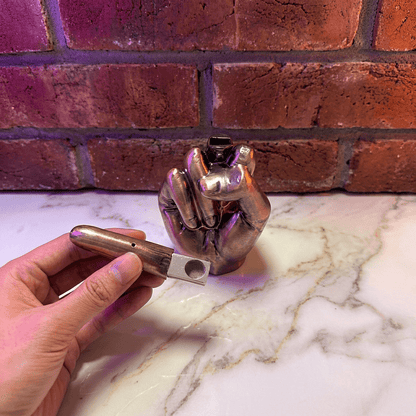 Middle Finger Grinder & Pipe Combo – Heavy Duty 2 - in - 1 SystemMetal hand pipe held by a hand on a marble surface with a brick wall background