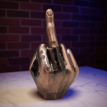 Middle Finger Grinder & Pipe Combo – Heavy Duty 2 - in - 1 SystemMetallic hand grinder with a middle finger pointing upwards on a textured surface with a brick wall background.