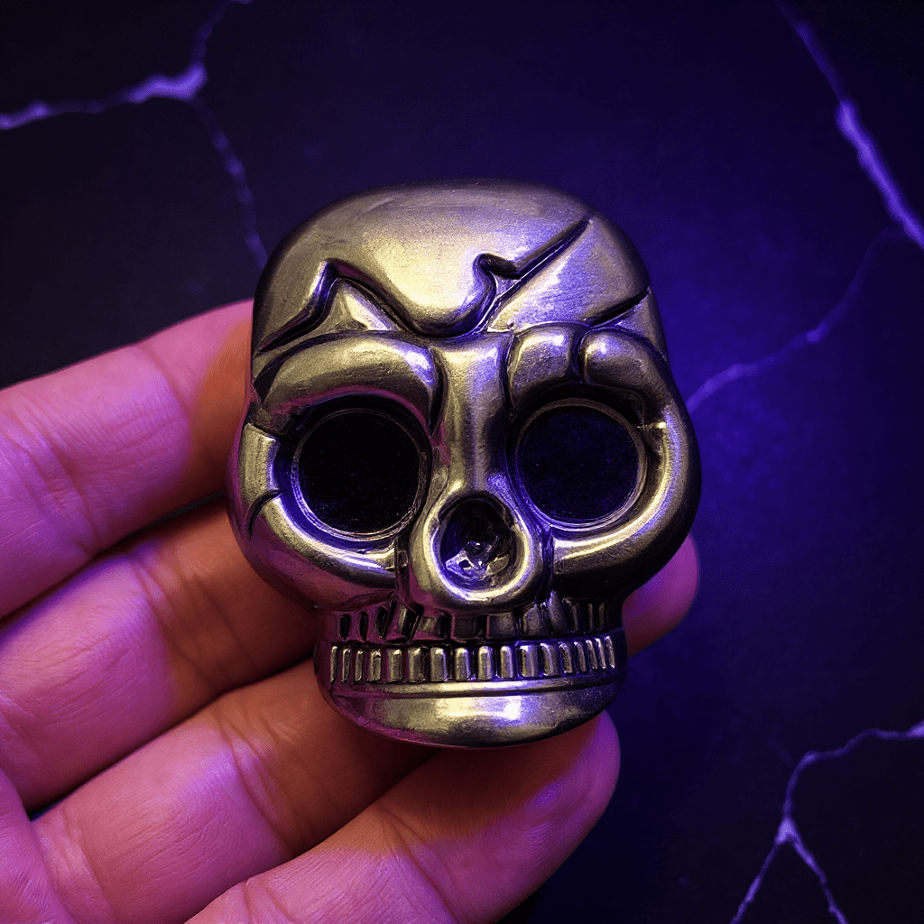 Mini Skull Herb Grinder – Vintage Bronze - Metallic skull shaped grinder held in a hand with a dark background