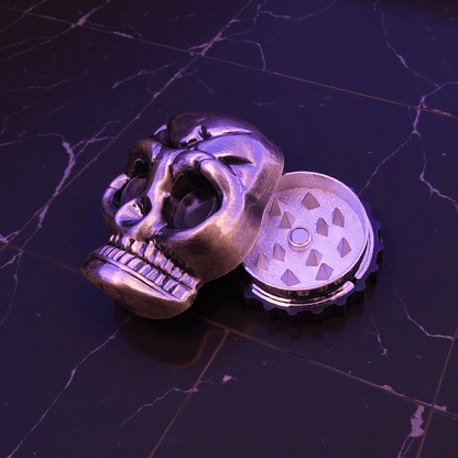 Mini Skull Herb Grinder – Vintage Bronze- Skull shaped herb grinders on a dark marble surface