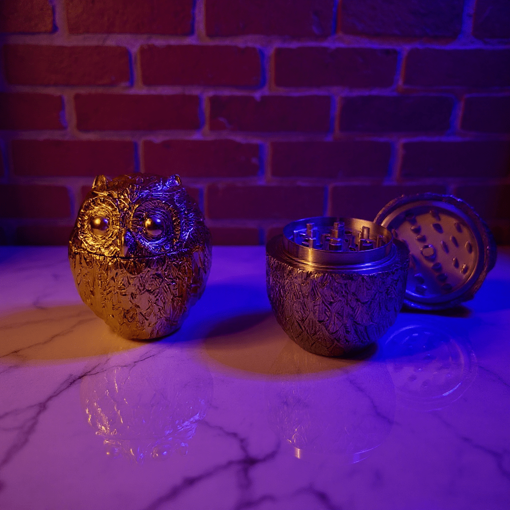 Decorative owl - shaped grinders on a marble surface with a brick wall background.