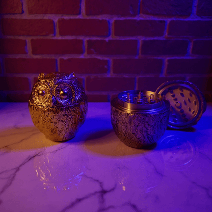 Decorative owl - shaped grinders on a marble surface with a brick wall background.
