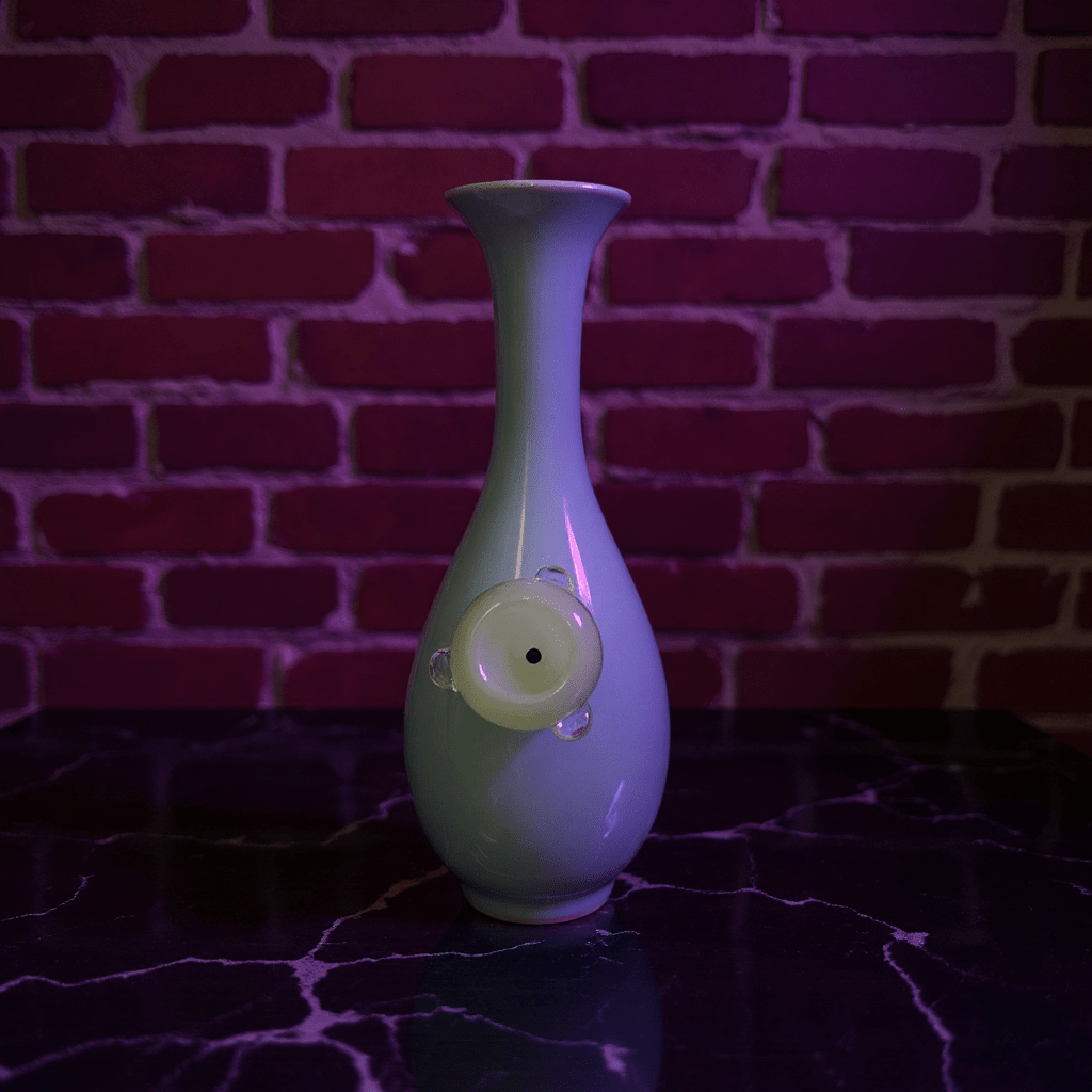 Pale Blue Flared Top Celadon Porcelain BongGreen ceramic bong with a unique design glass bowl on a dark surface
