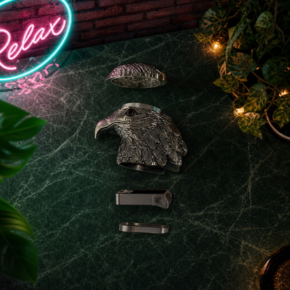Metallic eagle head herb grinder on a dark surface with a neon 'Relax' sign in the background.