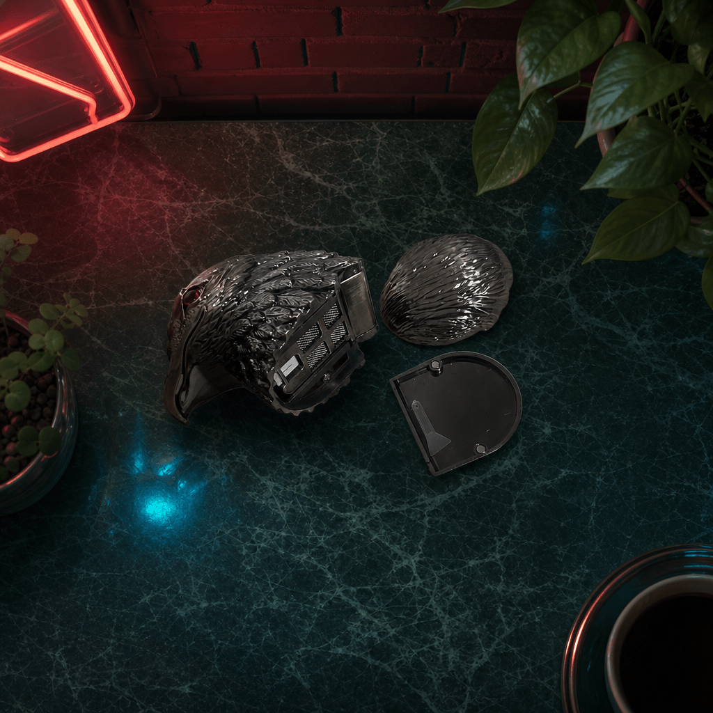 Patriot Eagle Head Metal Grinder – Brass, Bronze & Black FinishBlack herb grinder on a dark surface with plants and neon lights in the background
