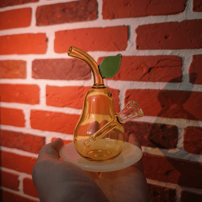 Pear Glass Bong – Mini Fruit Water Pipe with Bowl - Glass smoking bong shaped like a pear with a leaf on a white plate