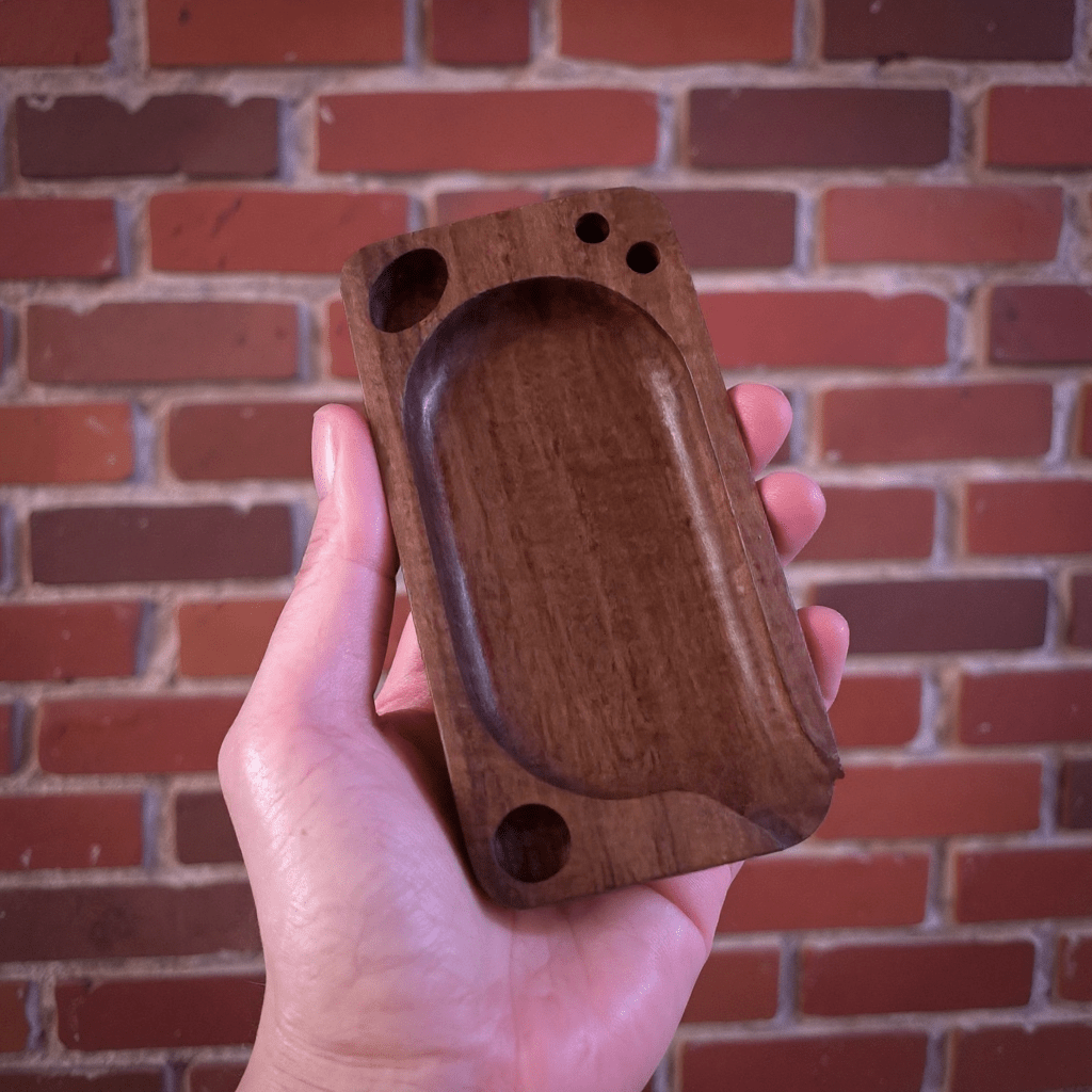 Premium Wooden Rolling Tray - Preset Tool for SmokingHand holding a wooden rolling tray against a brick wall background