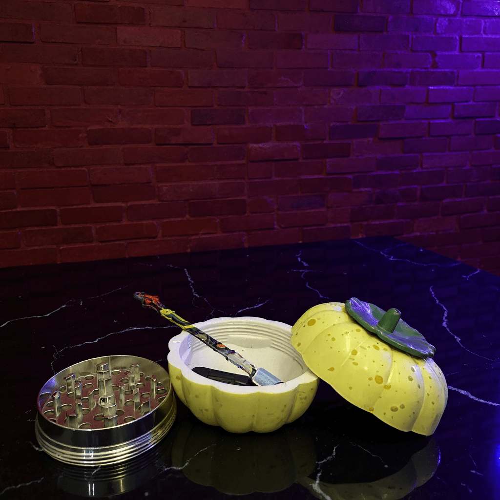 Pumpkin Herb Grinder – 3 - Piece Grinder Yellow pumpkin - shaped grinder with a metallic grinder on a reflective surface
