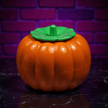 Pumpkin Herb Grinder – 3 - Piece GrinderPumpkin - shaped herb grinders with a green lid on a dark surface