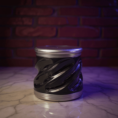 Spiral Grip Aluminum Herb Grinder - Black and silver tobacco grinder on a reflective surface with a brick wall background