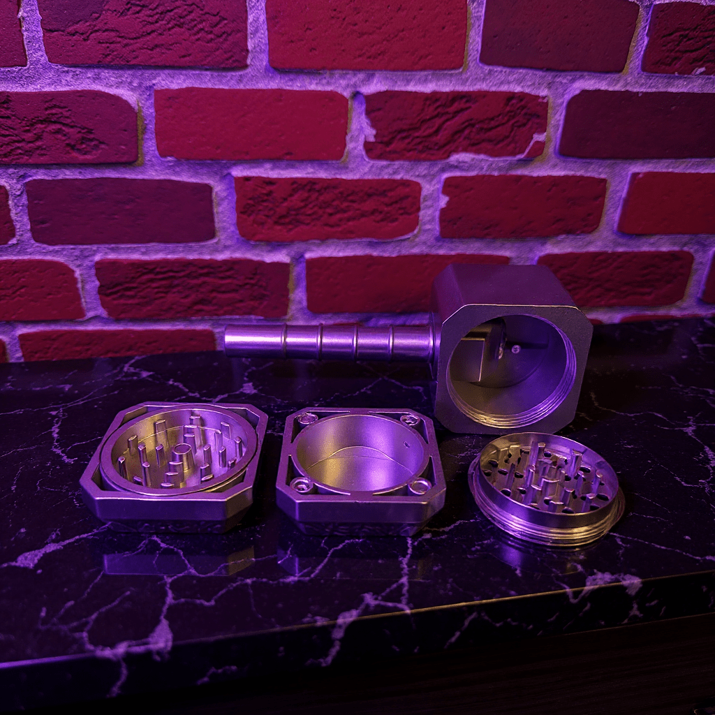 Thor Hammer Shape Grinder – 4 - Part Metal GrinderA silver hammer grinder set on a dark surface with a brick wall background