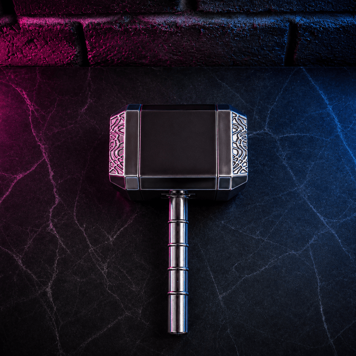 Thor Hammer Shape Grinder – 4-Part Metal GrinderA miniature replica of Thor's hammer (Mjolnir) with a black rectangular head and silver-toned metallic handle, centered on a dark textured surface with dramatic pink and blue lighting.
