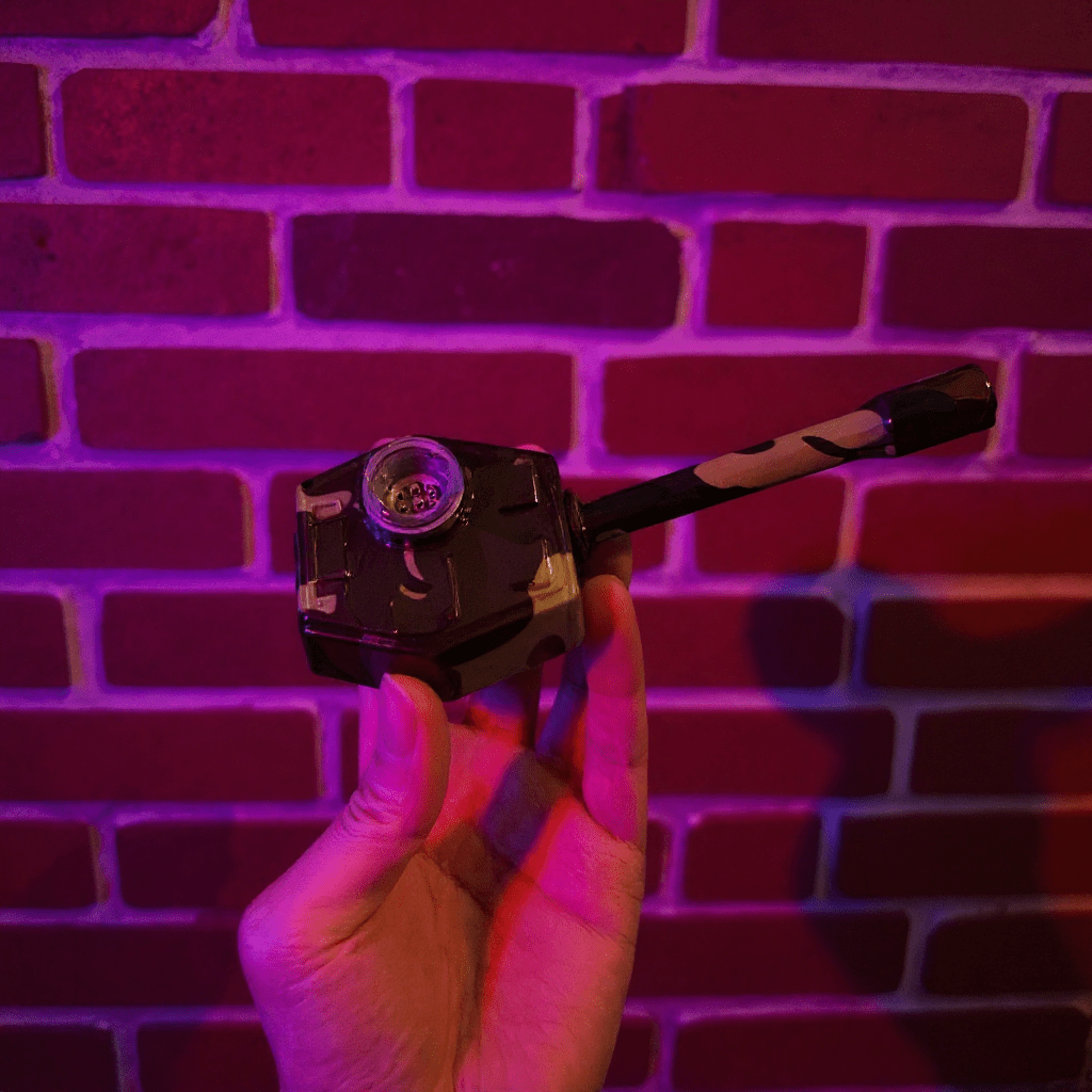 Hand holding tiger panzer pipe against a brick wall with purple lighting