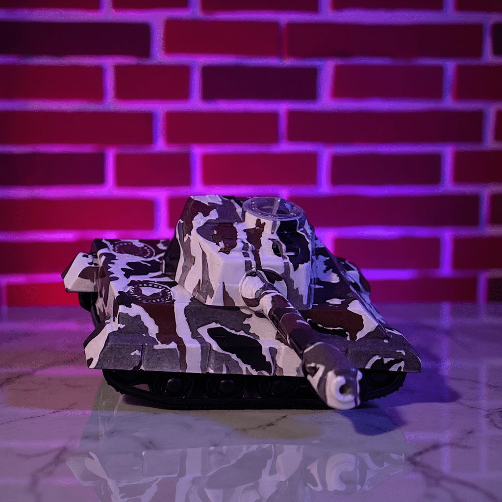 Camouflage - patterned toy tank grinder on a reflective surface with a brick wall background