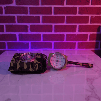 metallic grinder set with camouflage patterns on a reflective surface with a brick wall background.
