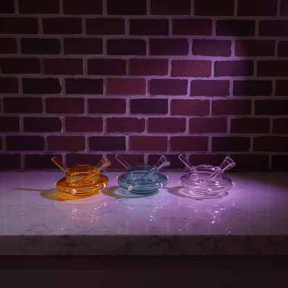 UFO Mini Glass Bong – Water Pipe in 3 ColorsThree colorful glass water pipe on a marble surface with a brick wall background